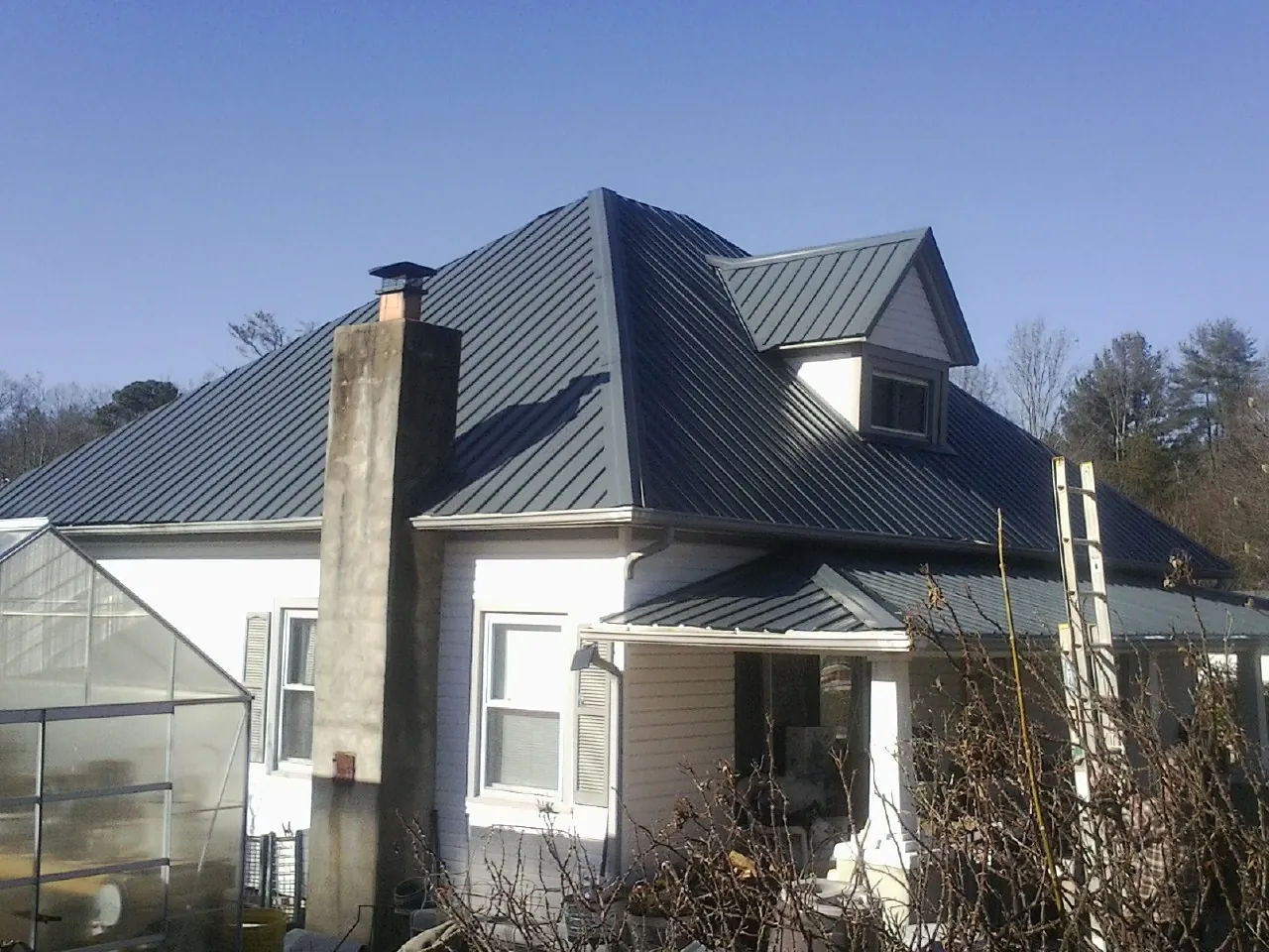 Dark blue standing seam metal roof on a white farmhouse with dormer — Slate & Tile Roof Repair by Roofing Brothers in Cartersville
