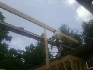 Carpenter setting a ridge beam over a new addition frame — Ice Dam Removal by Roofing Brothers in Cartersville