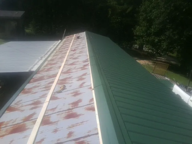 Old rusted panels beside newly installed green metal roofing — Wind Damage Roof Repair by Roofing Brothers in Cartersville