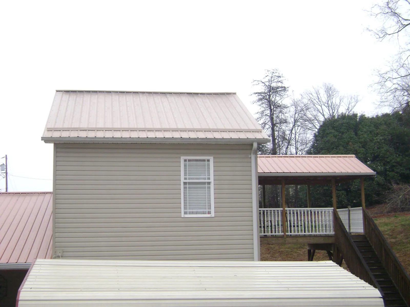 Tan metal roofs on a two story addition and attached porch, from a Roof Replacement job in Cartersville