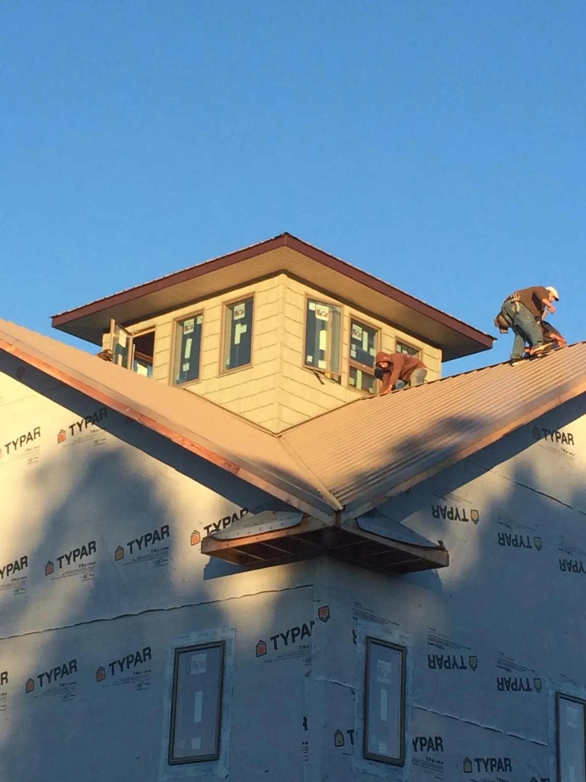 Roofers working around a rooftop cupola on a new metal roof at sunset — Roof Waterproofing in Cartersville by Roofing Brothers